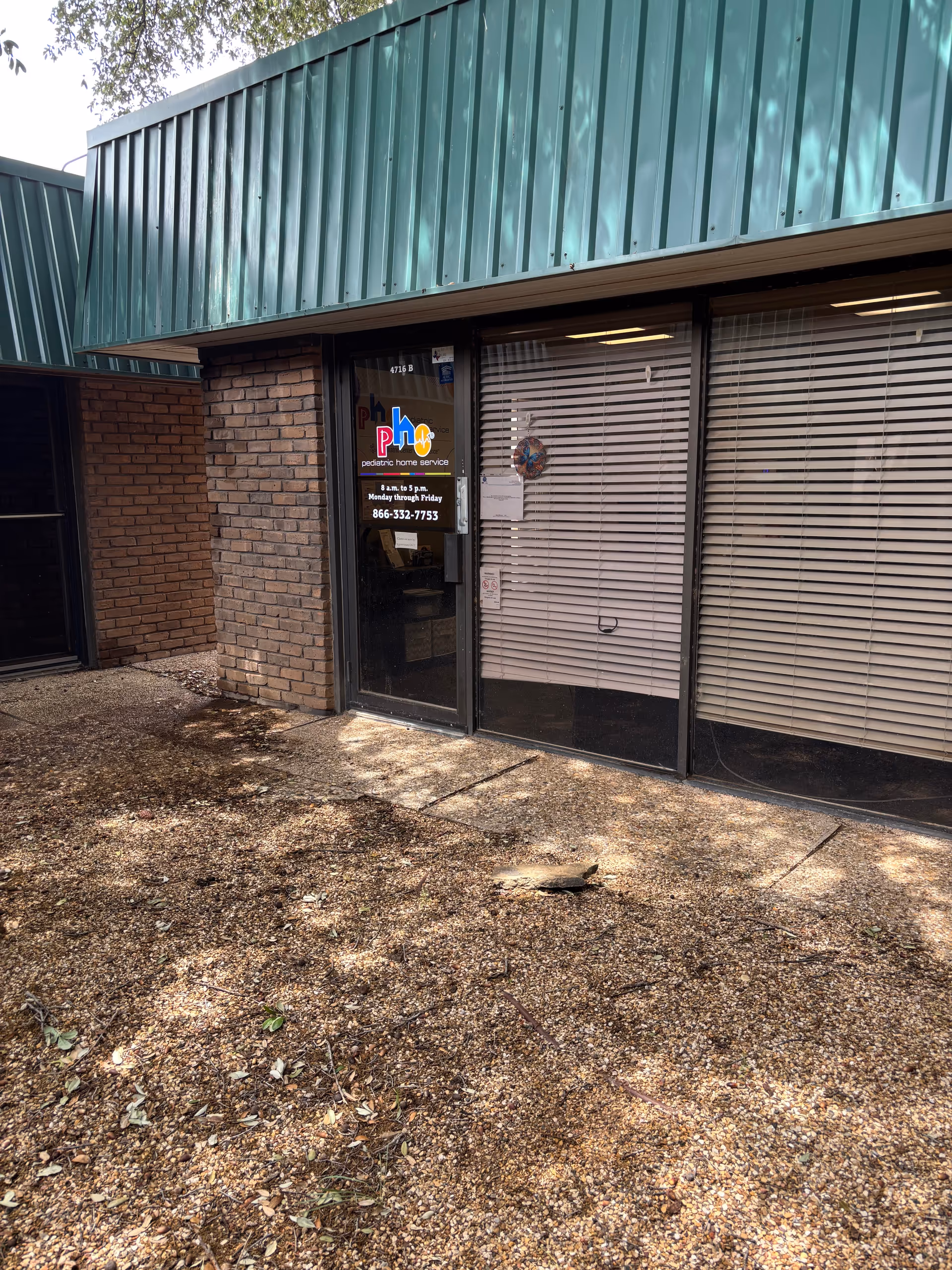 Exterior brick building with green metal awning, glass door, and window blinds