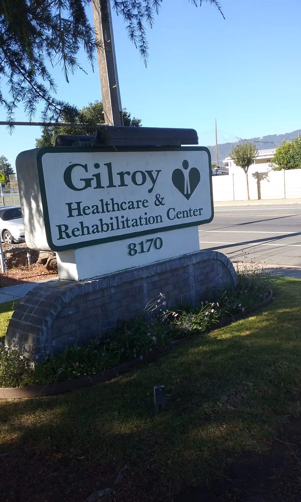 Outdoor street sign for Gilroy Healthcare & Rehabilitation Center with landscaping.