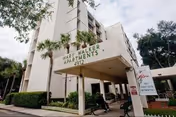 Exterior view of Mary Walker Towers apartment building entrance with a covered drop-off and palm trees.
