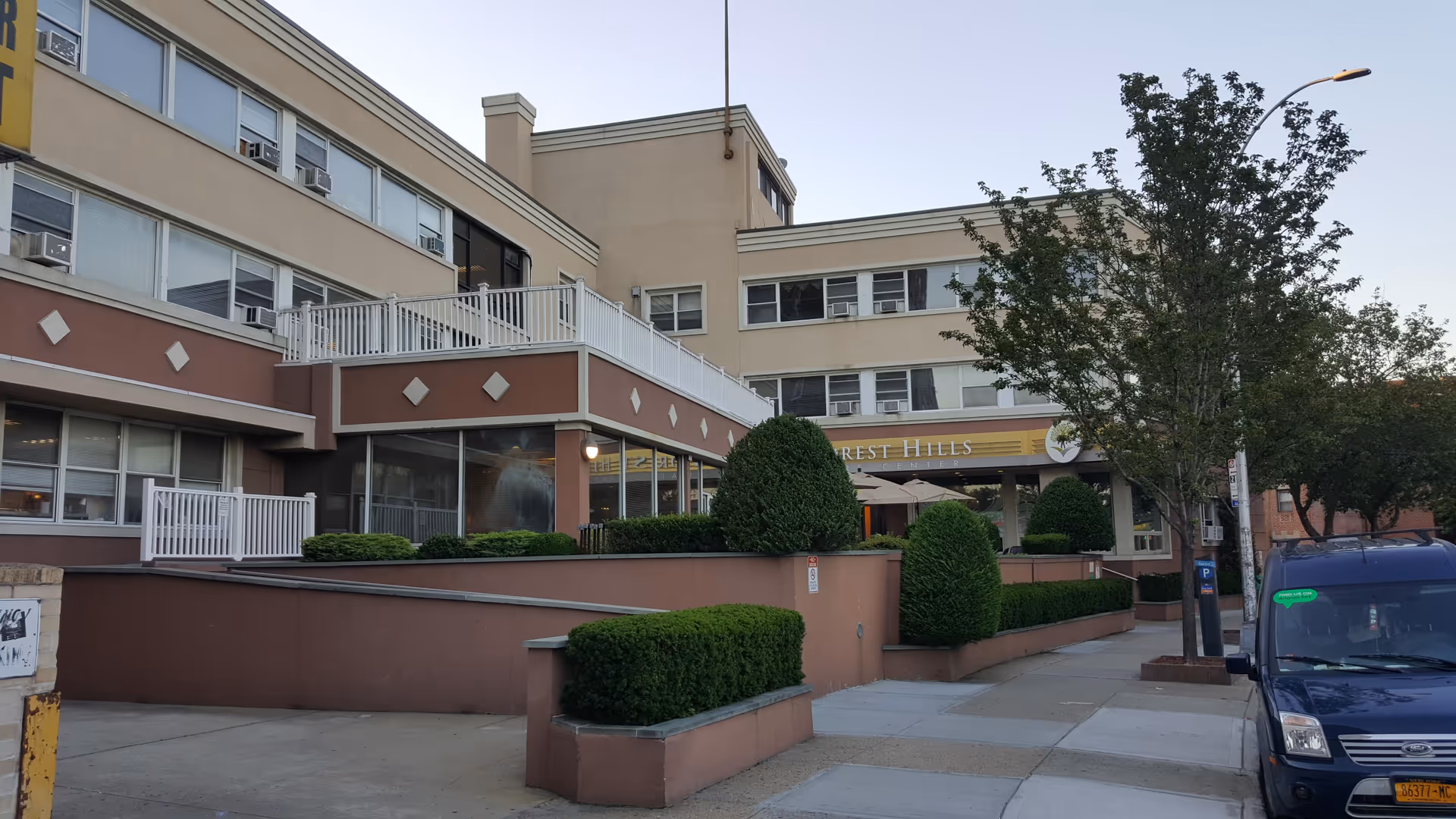 Exterior view of Forest Hills Care Center with a tan building, landscaping, and a sidewalk.