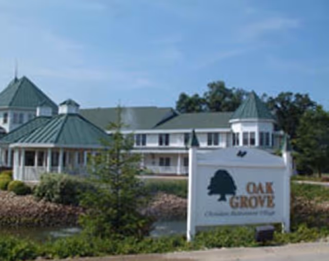 Exterior view of Oak Grove Christian Retirement Village with a sign and green-roofed buildings.