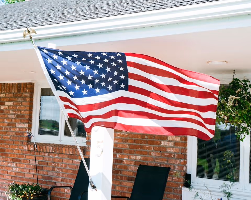 American flag on a porch in front of a brick senior living facility