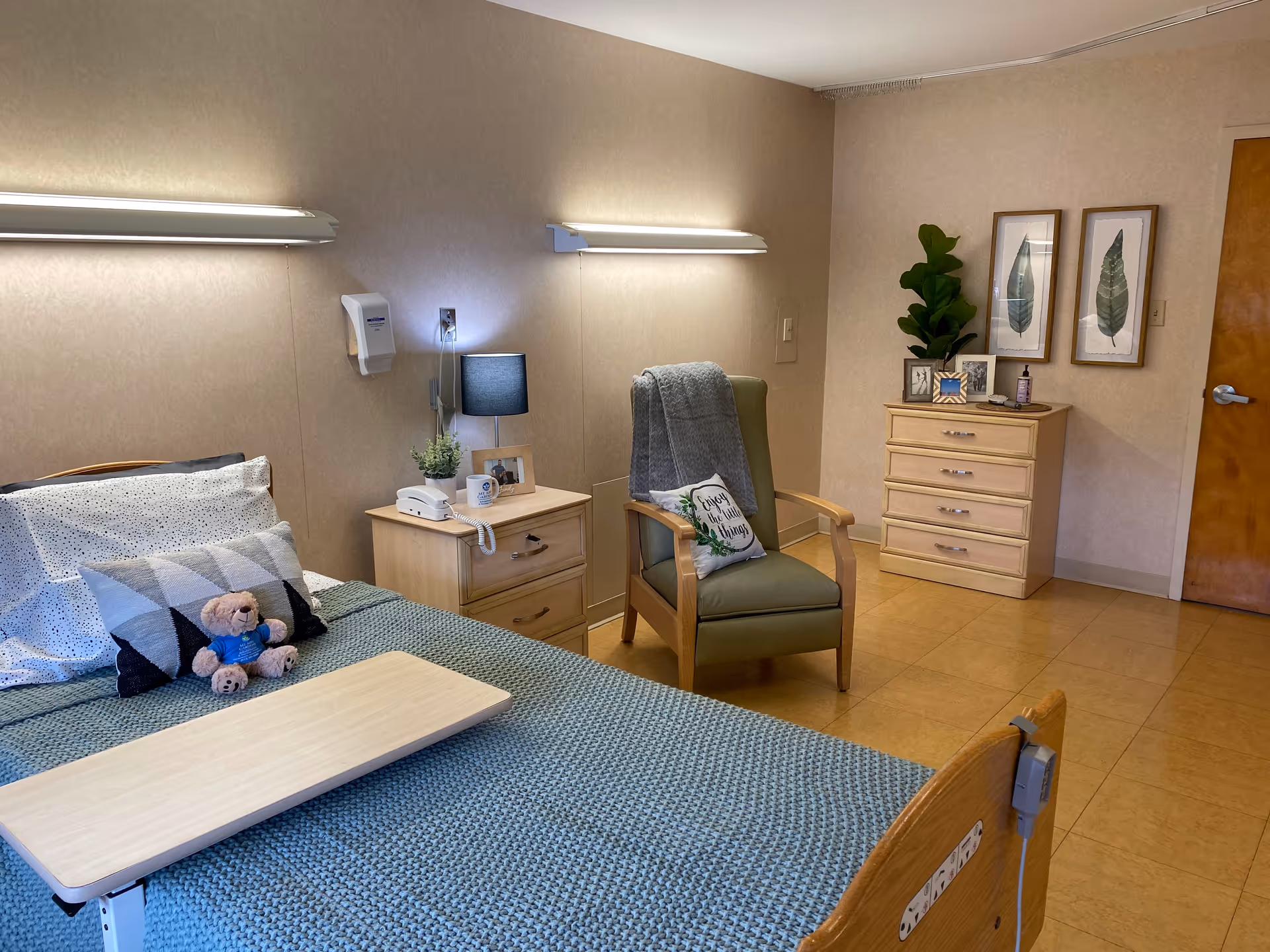 Senior living bedroom with bed, nightstands, chair, dresser, and wall art.