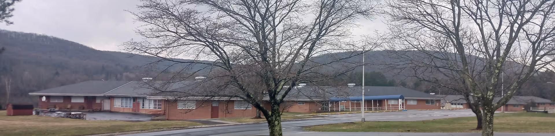 Long, low brick senior living facility with leafless trees and parking lot.