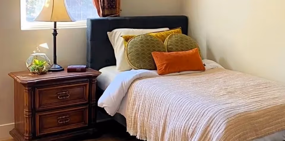 Cozy bedroom with a bed, nightstand, lamp, and decorative pillows.