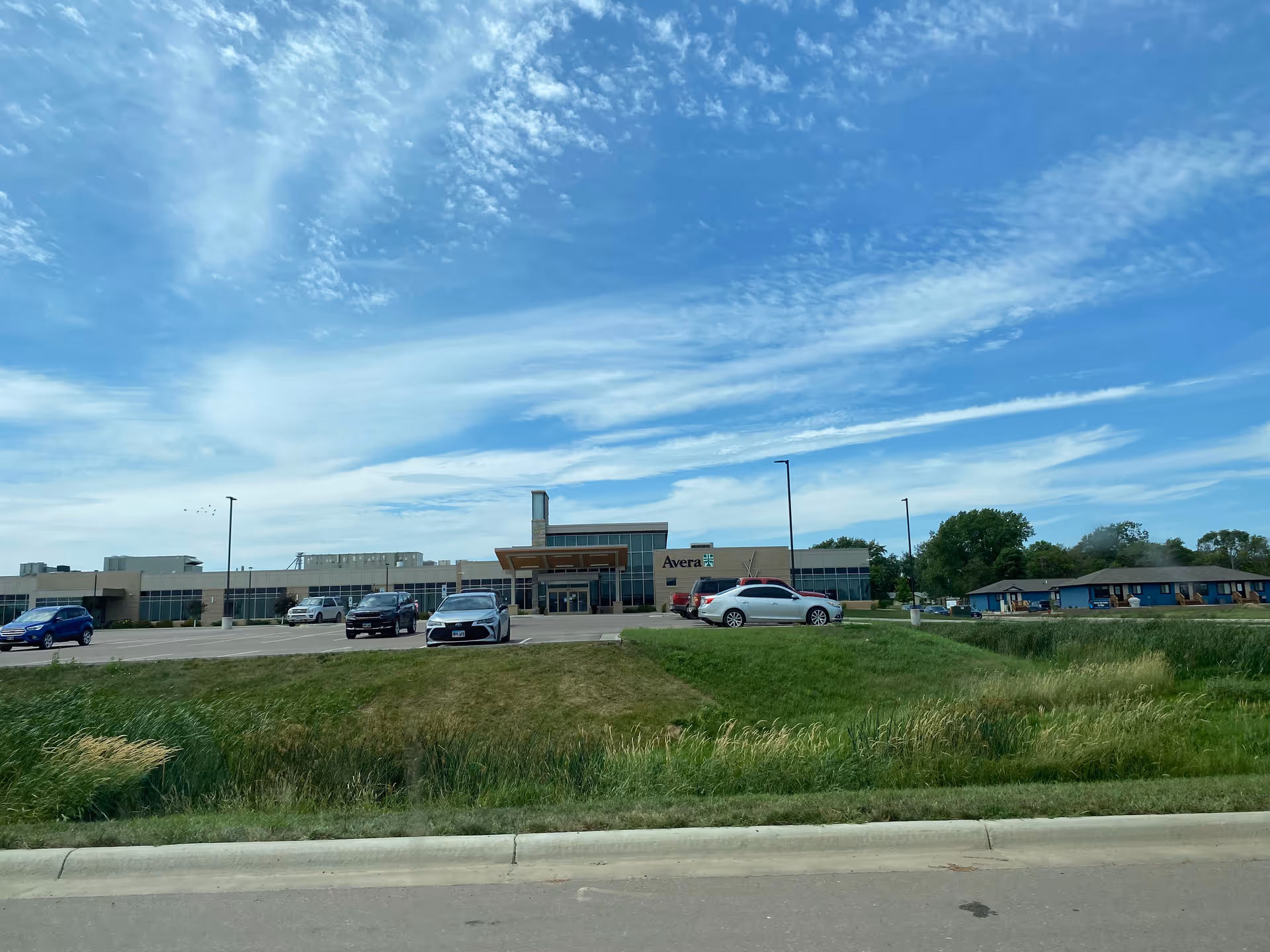 Exterior view of Avera Gregory Hospital front with cars and blue sky.