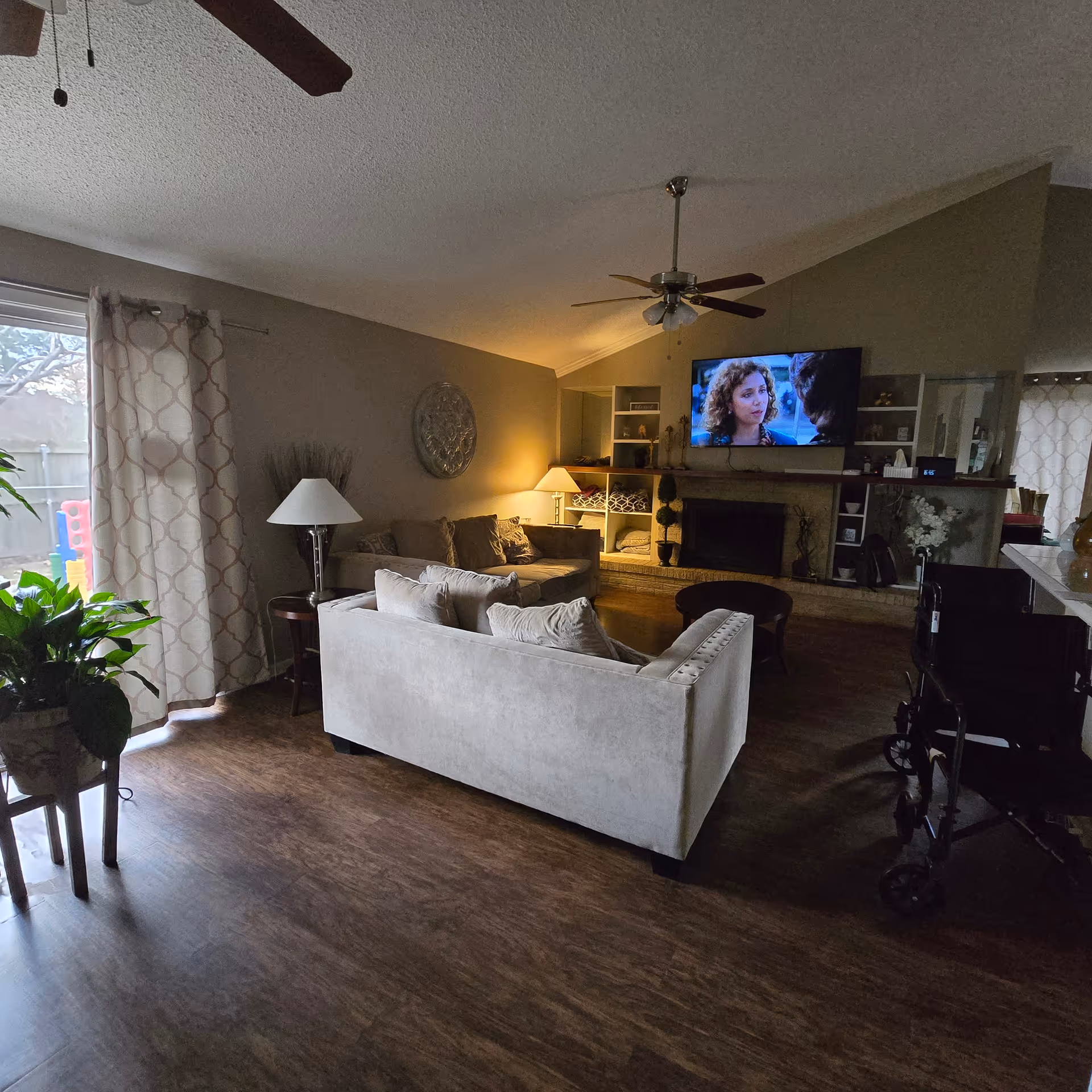 Cozy living room with sofas, fireplace, TV, and a wheeled mobility device nearby.