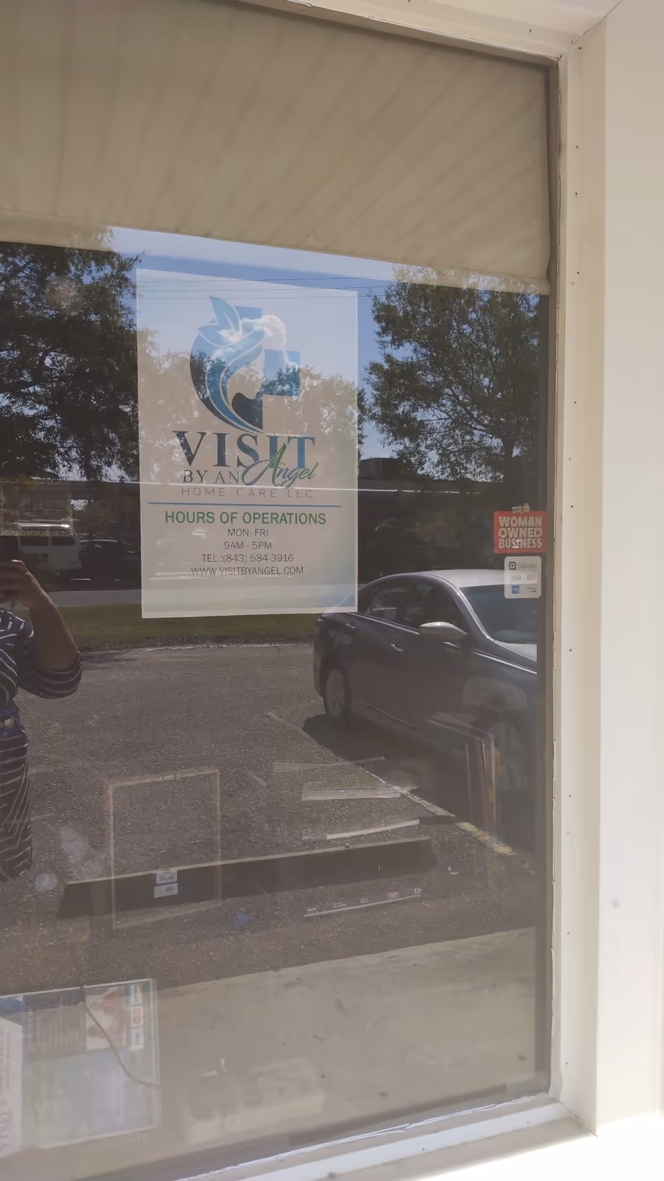 Window sign for Visit By An Angel Home Care is visible, with a parked car reflected.