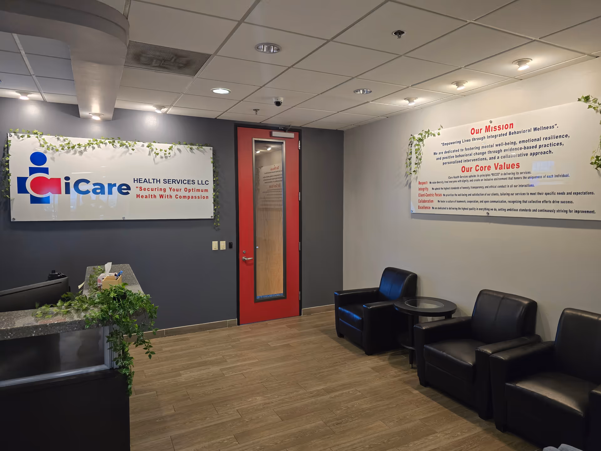 Office lobby with iCare Health Services sign, red door, reception desk, and black leather seating.
