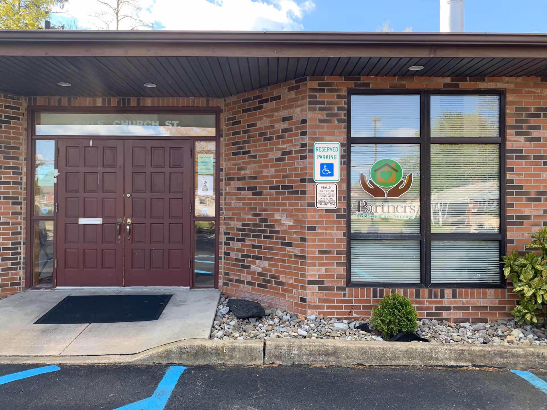 Brick building entrance with double doors and window displaying Partners logo.