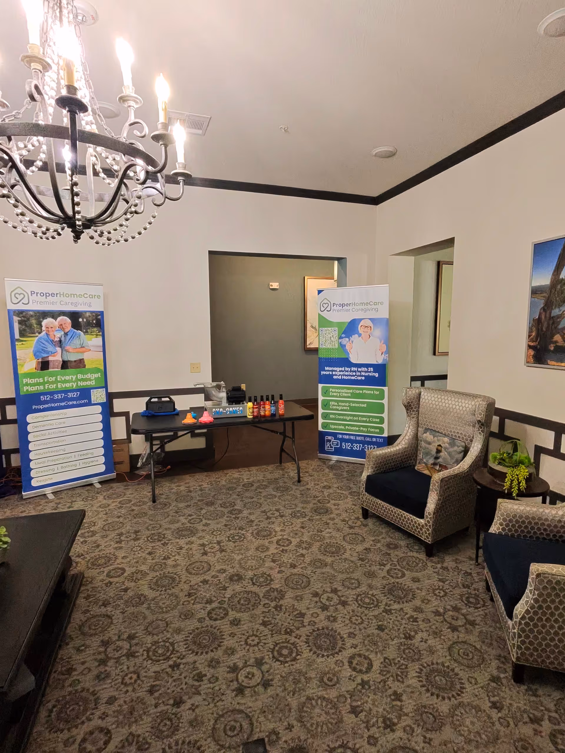 A furnished lobby with banners, chairs, and a chandelier in a senior care facility.