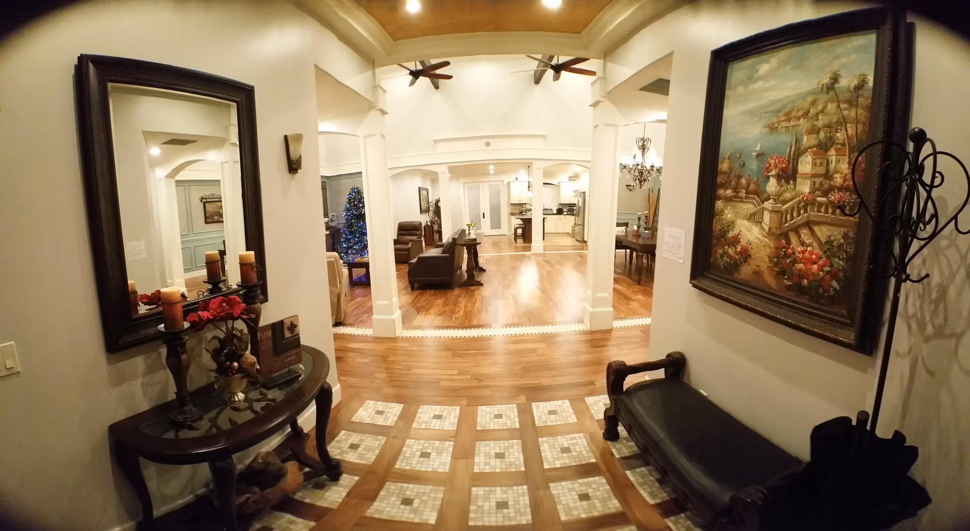 Bright interior foyer with archways, artwork, mirror, and seating leading to a spacious living area.