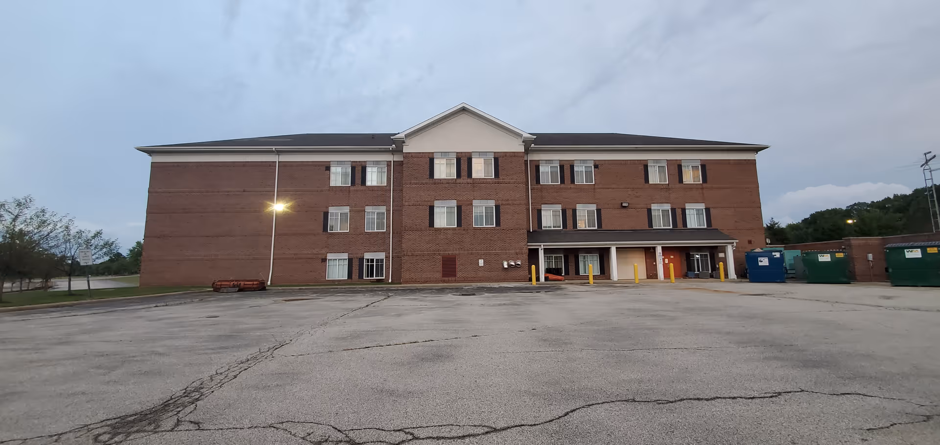A brick three-story senior living facility front with a large parking lot