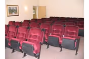 Rows of red theater seats fill a small auditorium-style room.
