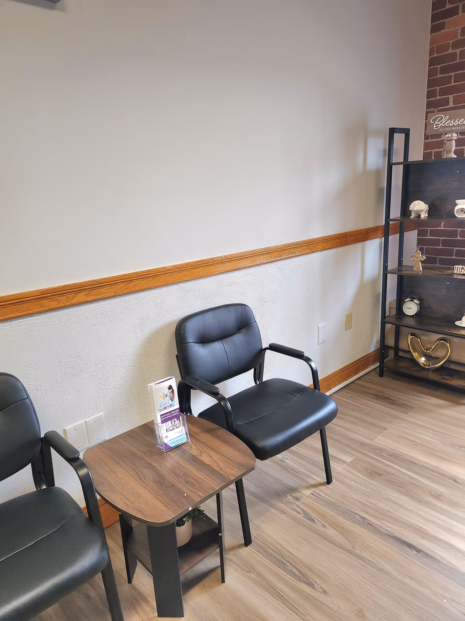 Two black chairs with a small table in a waiting area.