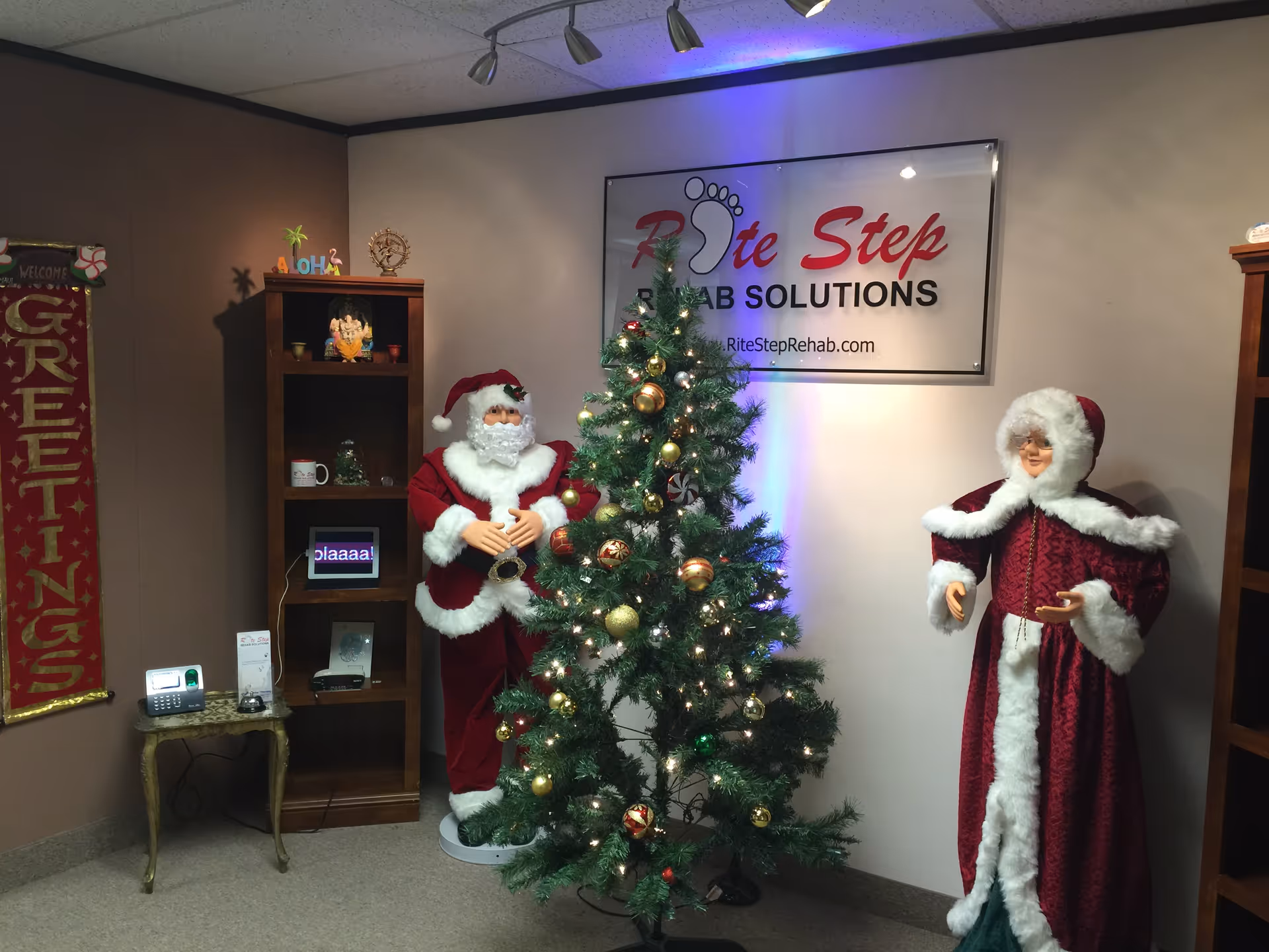 Indoor reception area featuring a Christmas tree, Santa figures, and a Rite Step Rehab Solutions sign.