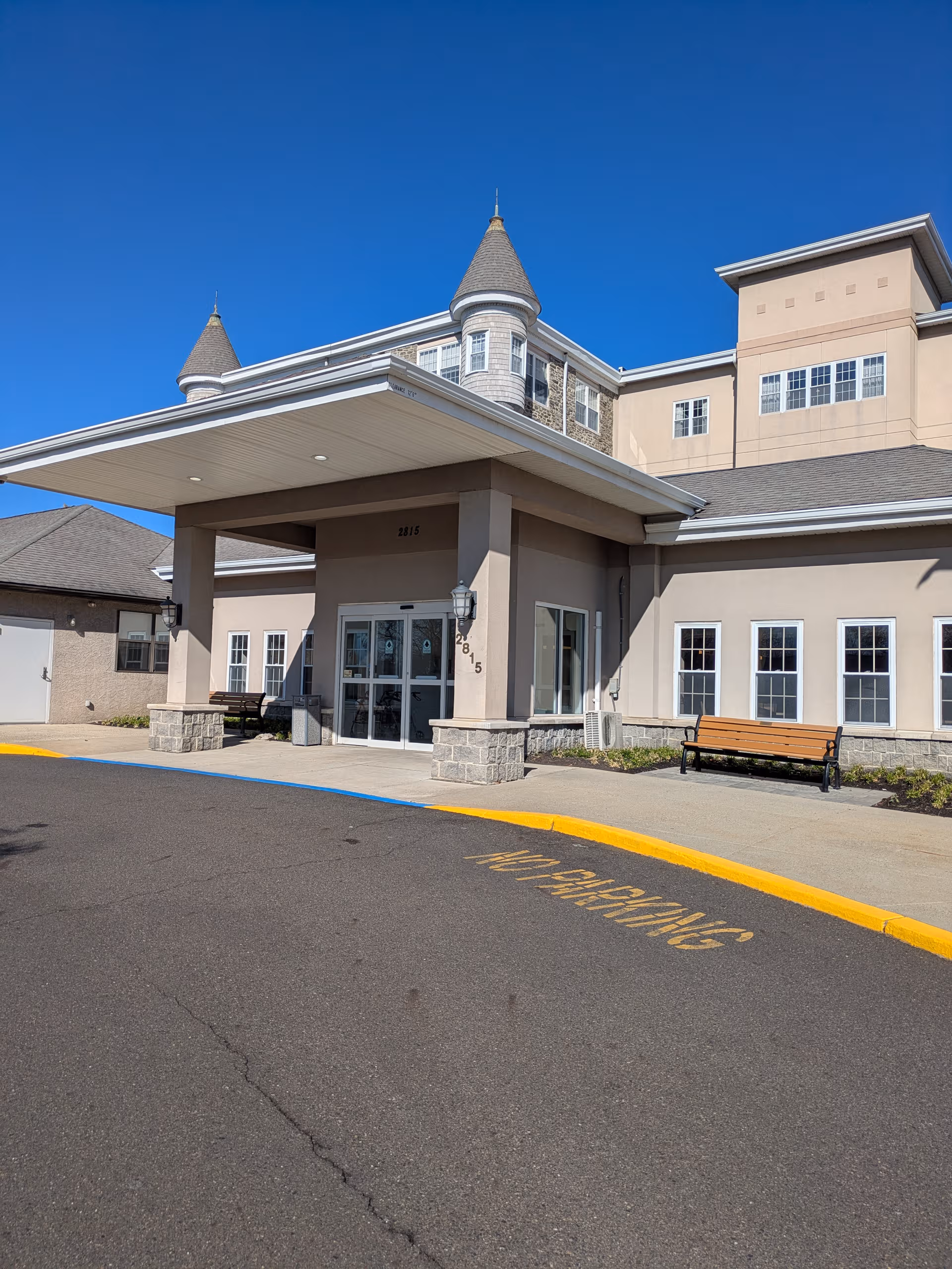 Exterior view of Wesley Enhanced Living facility with a covered entrance and benches.