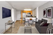 Open-concept living area in a senior facility with sofa, coffee table, dining table, and kitchen.