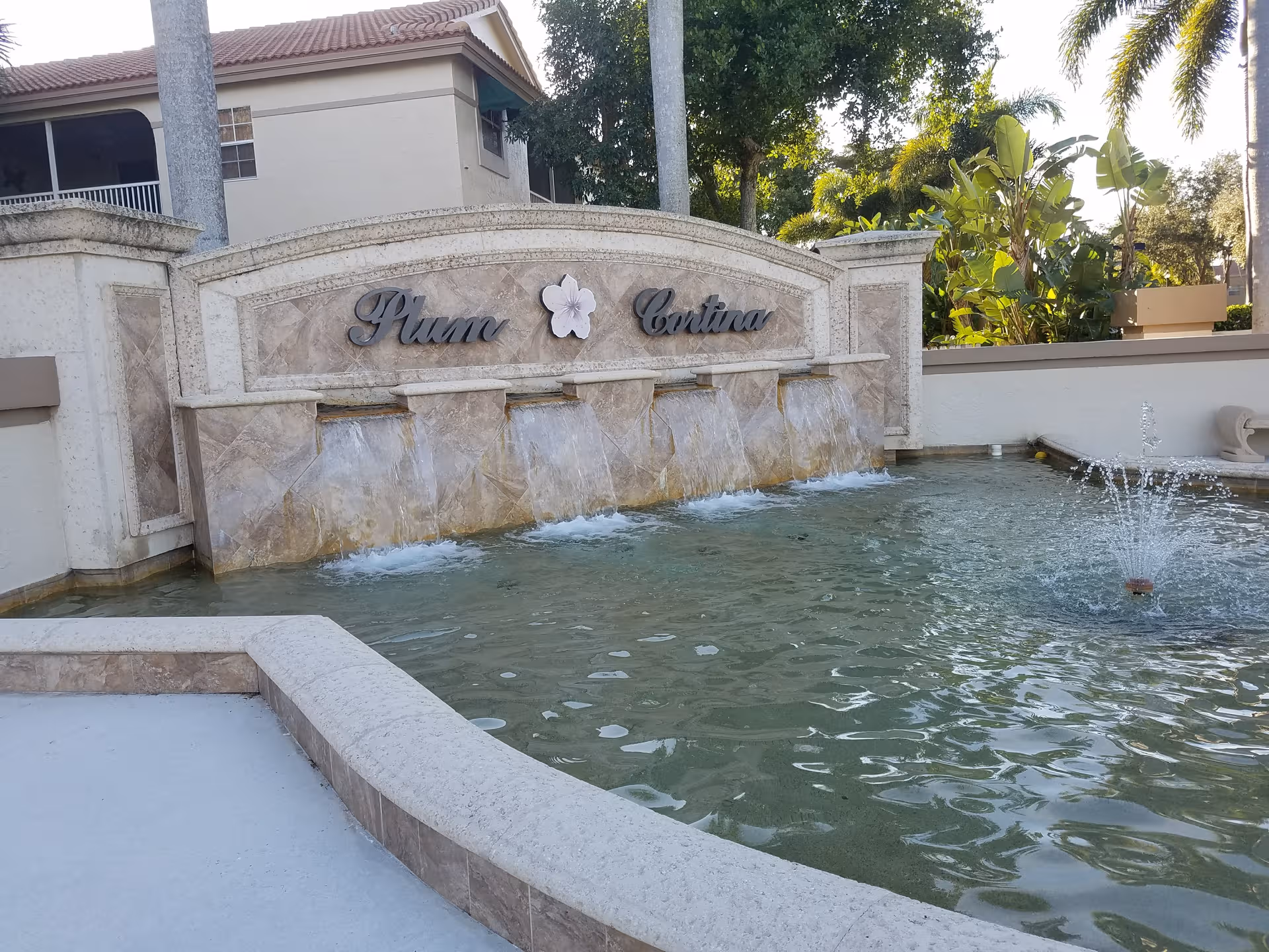Stone fountain wall with flowing water features in a courtyard at Stratford Court Boca Pointe.