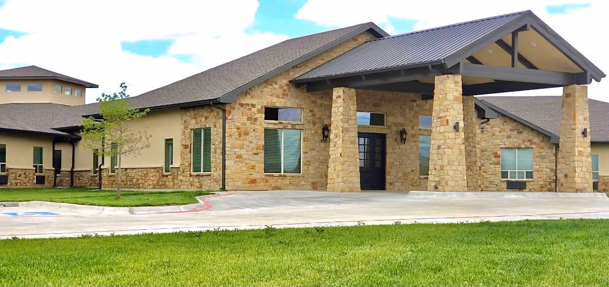 Front view of a stone-clad senior living facility with a covered entry.
