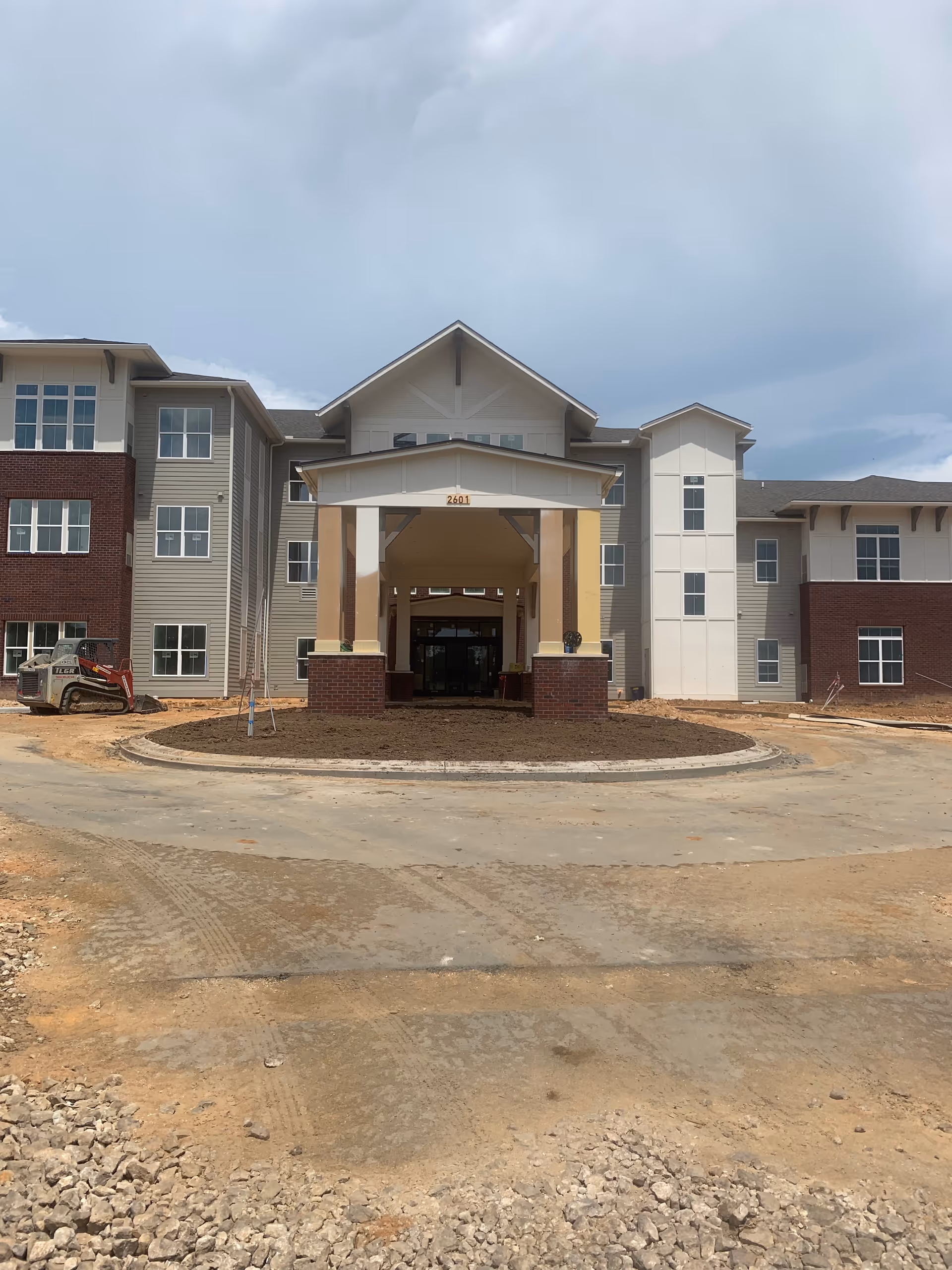 Front view of a multi-story senior living building under construction with a covered entrance.