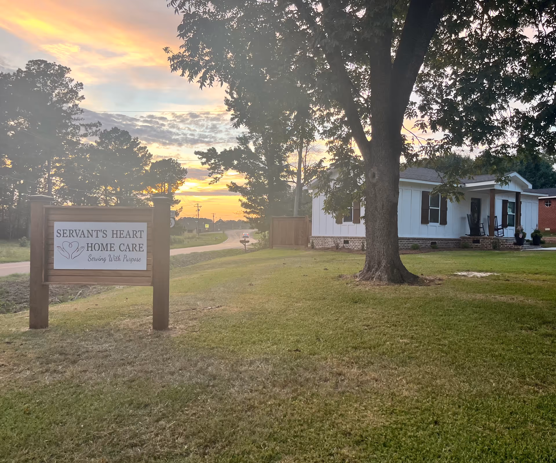 Exterior view of Servant's Heart Home Care building with sign on the lawn at sunset.