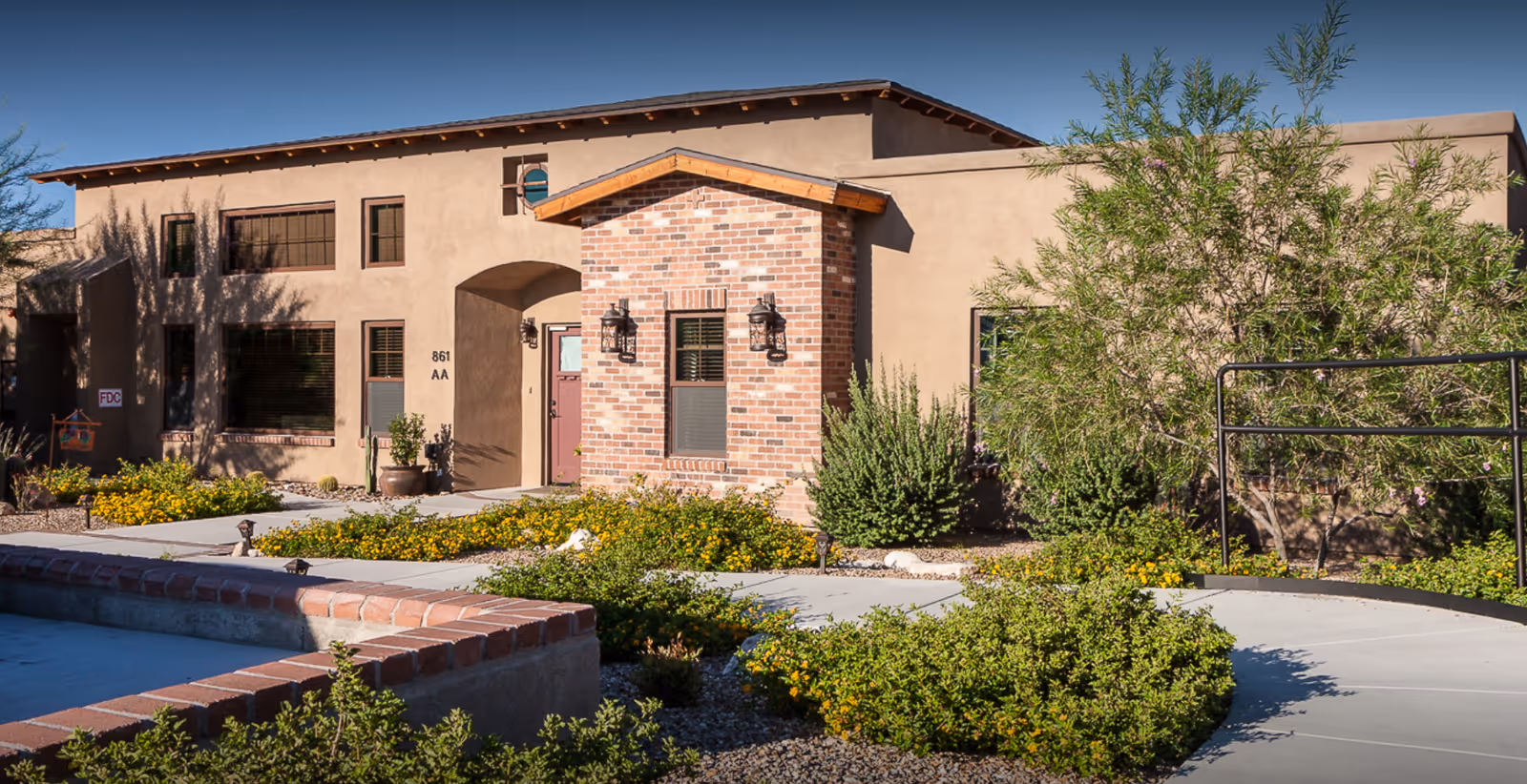 Exterior view of a senior living facility with brick entrance and manicured landscaping.