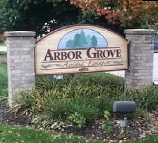 Stone entrance sign reading Arbor Grove Assisted Living and Memory Care, flanked by two stone columns.