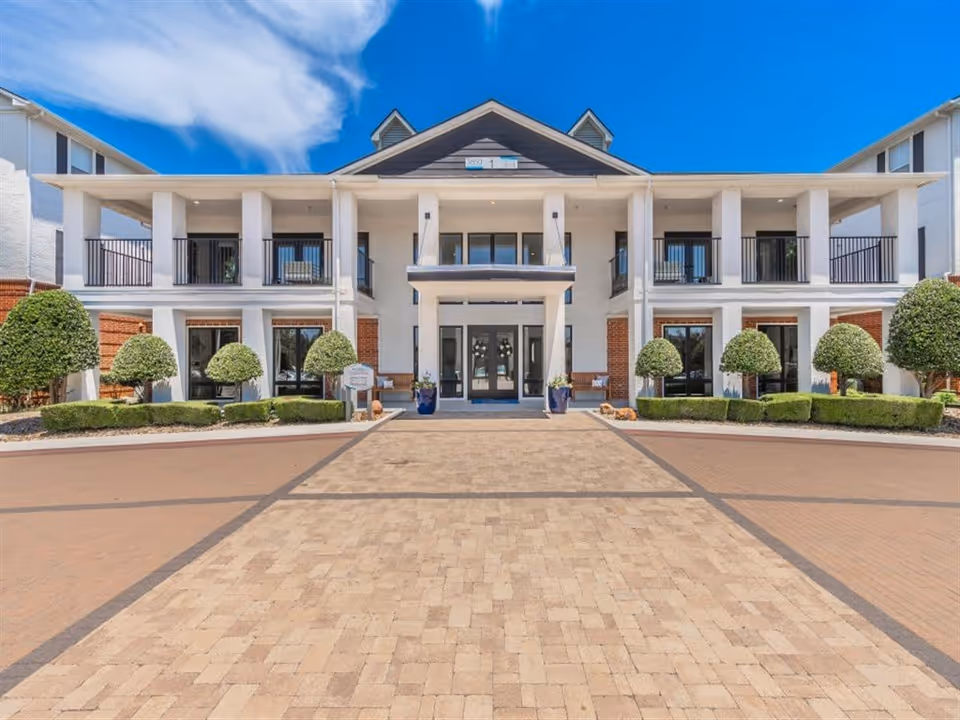 Front view of a modern senior living facility with a wide entrance and manicured shrubs.