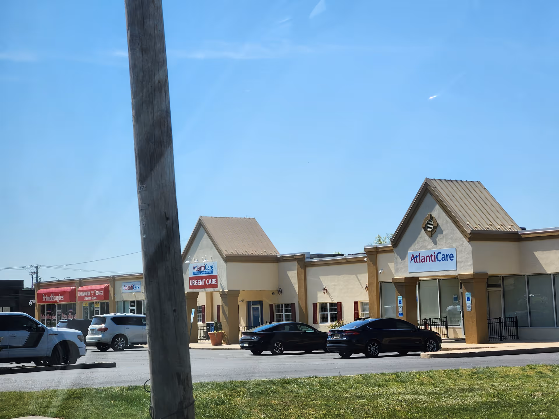 AtlantiCare building front with parked cars under a clear blue sky.