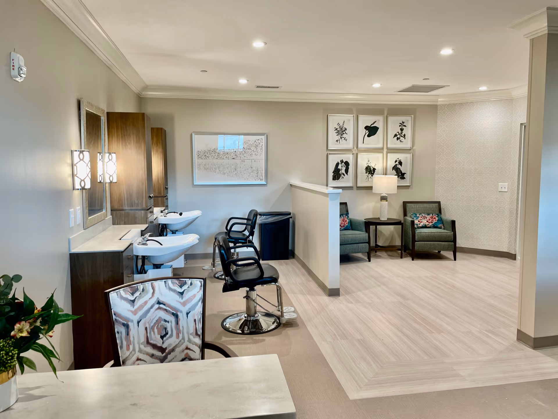 Interior common area with salon chairs, sinks, seating nook, and botanical wall art.