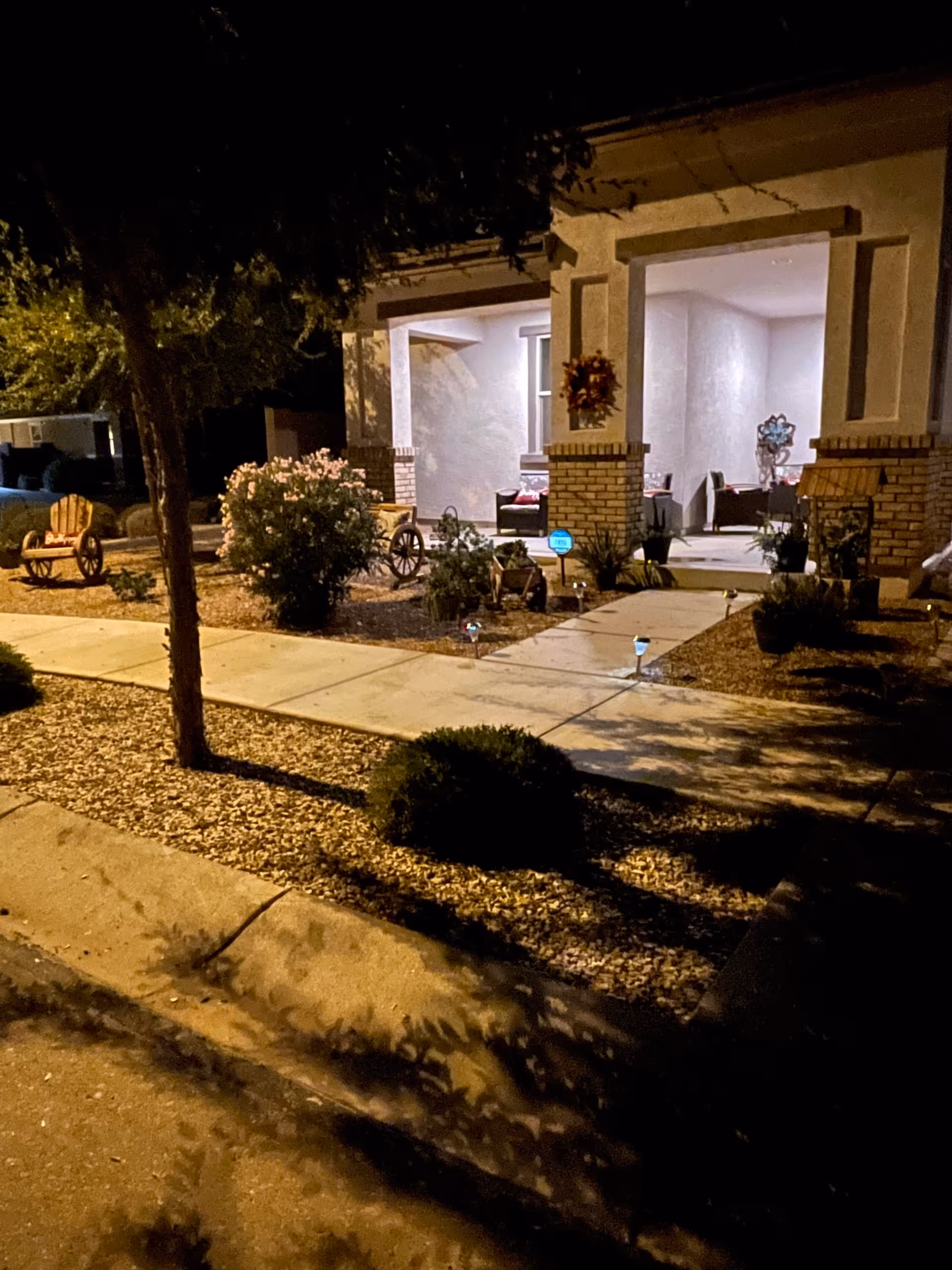 Nighttime exterior of a senior living facility with a lit front porch and seating.