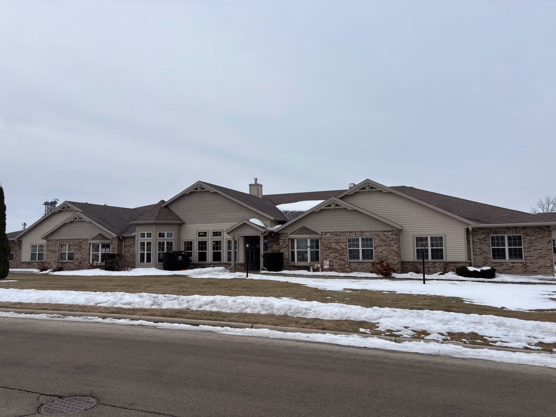 Snow on the ground in front of a single-story senior living facility.
