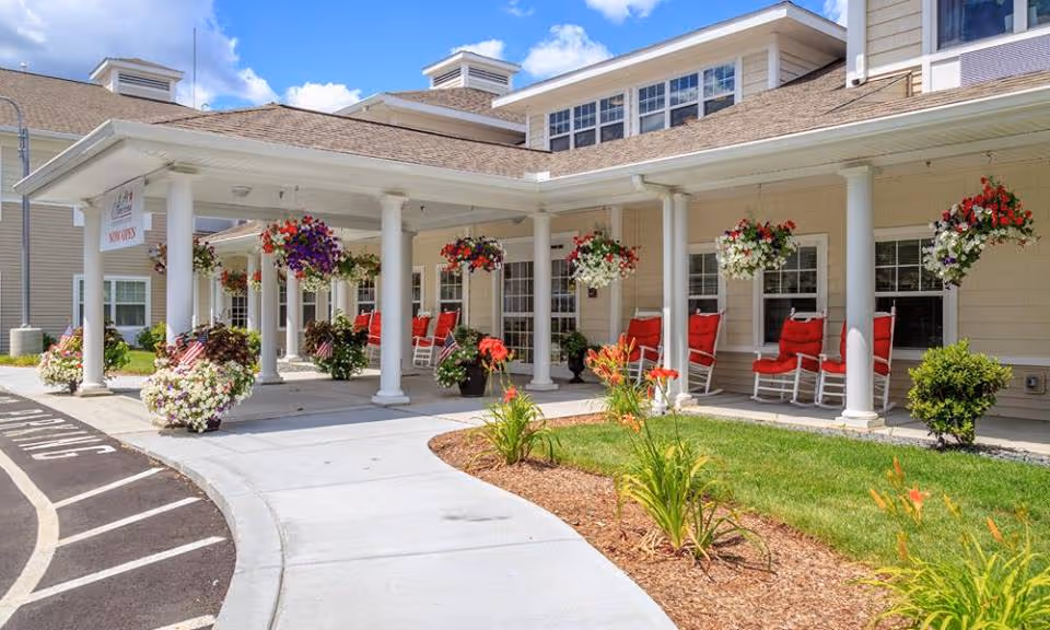 Exterior view of All American Assisted Living at Hillsborough with covered porch and red rocking chairs