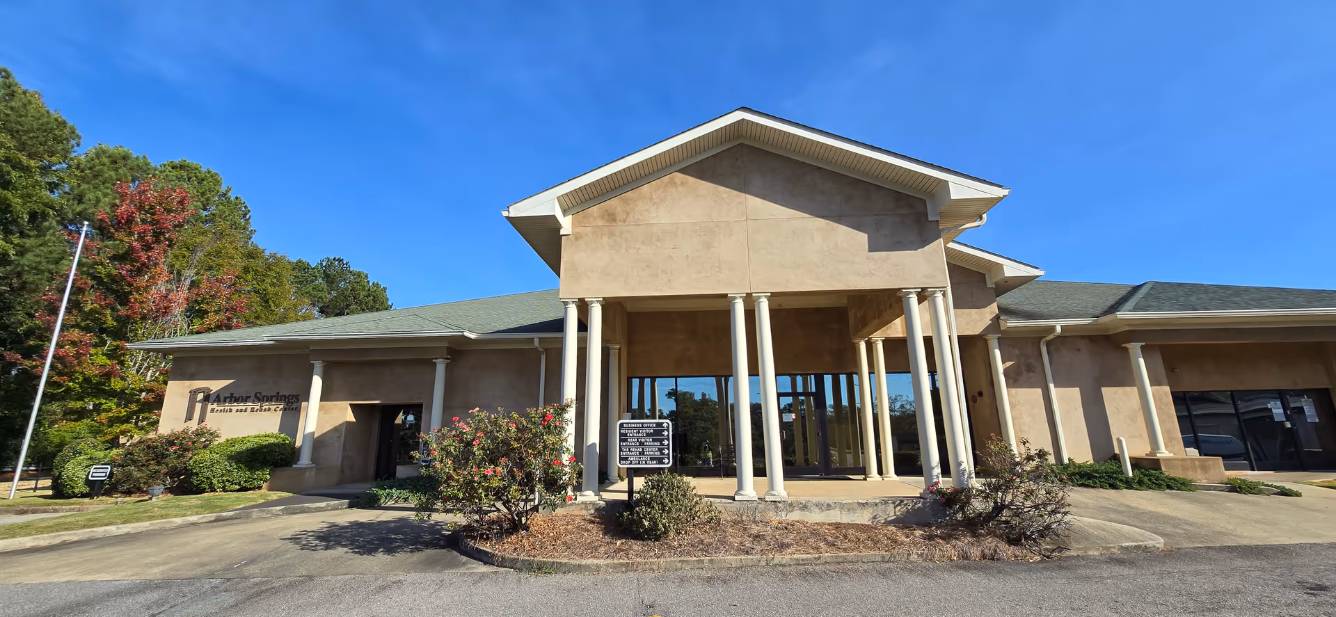 Arbor Springs Health and Rehab Center entrance, beige building with tall white columns and peaked roof.