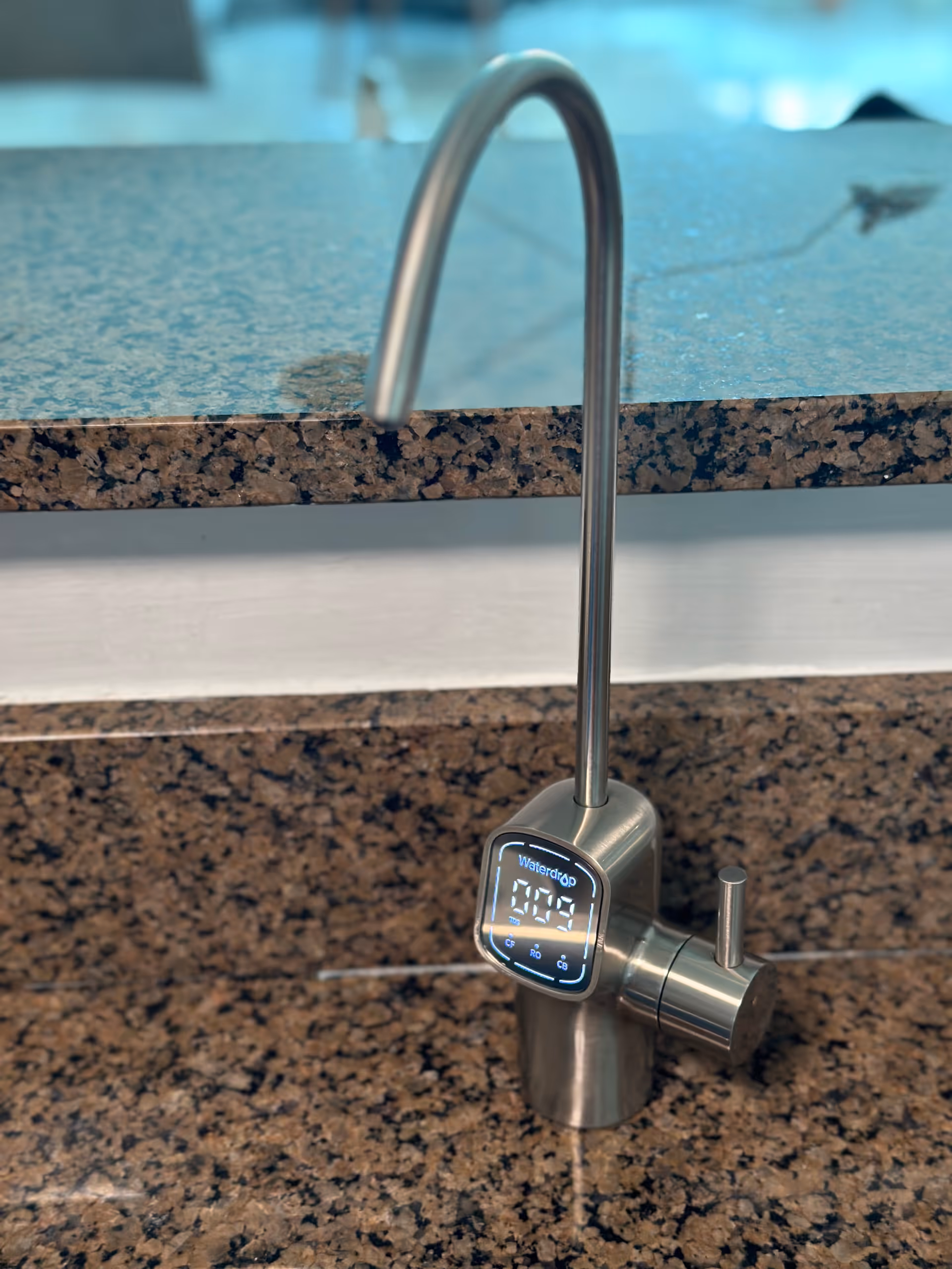 Close-up of a stainless steel kitchen faucet with a digital display on granite counter.