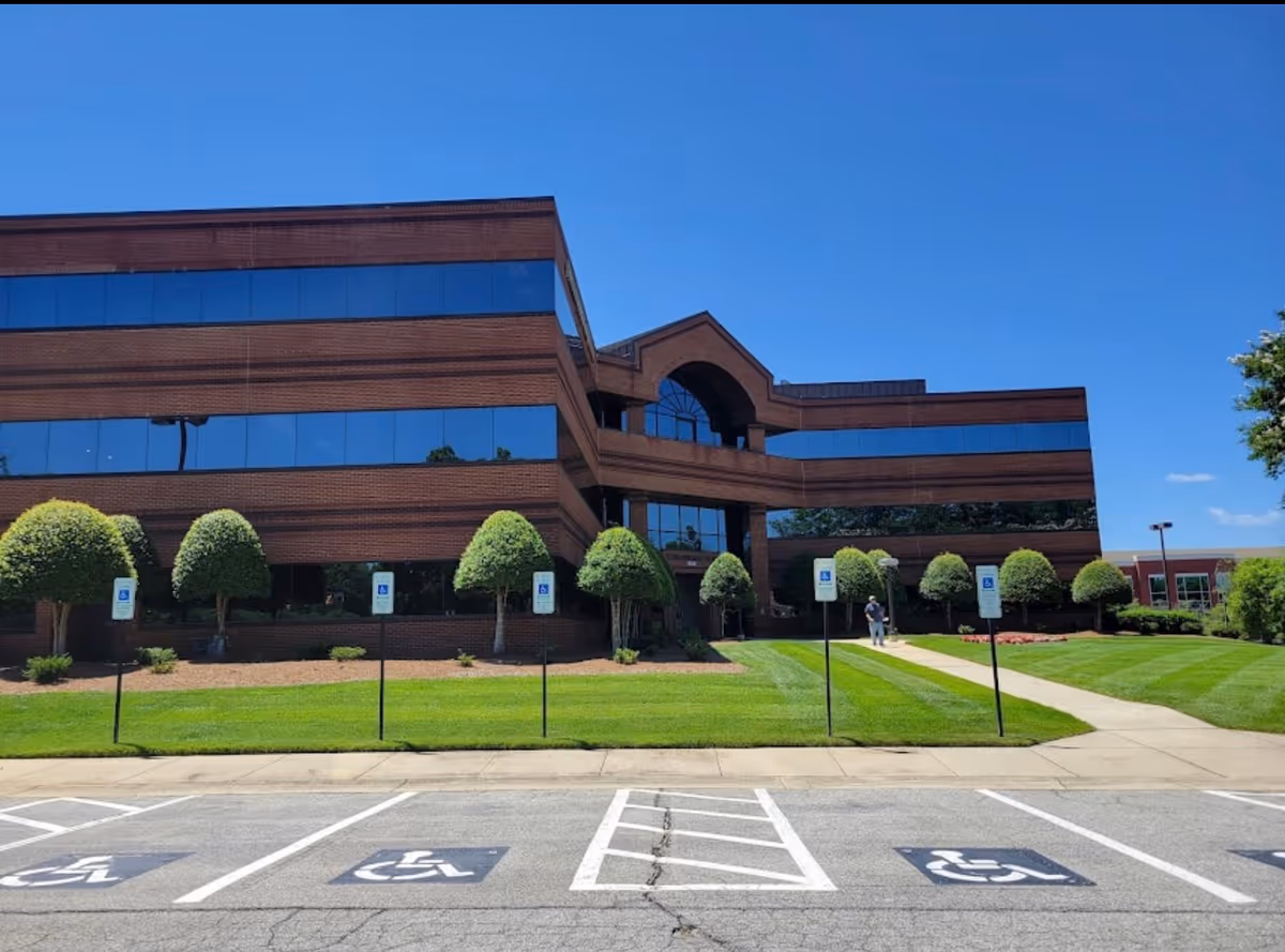 Brick office building exterior with blue-tinted windows and accessible parking spaces.