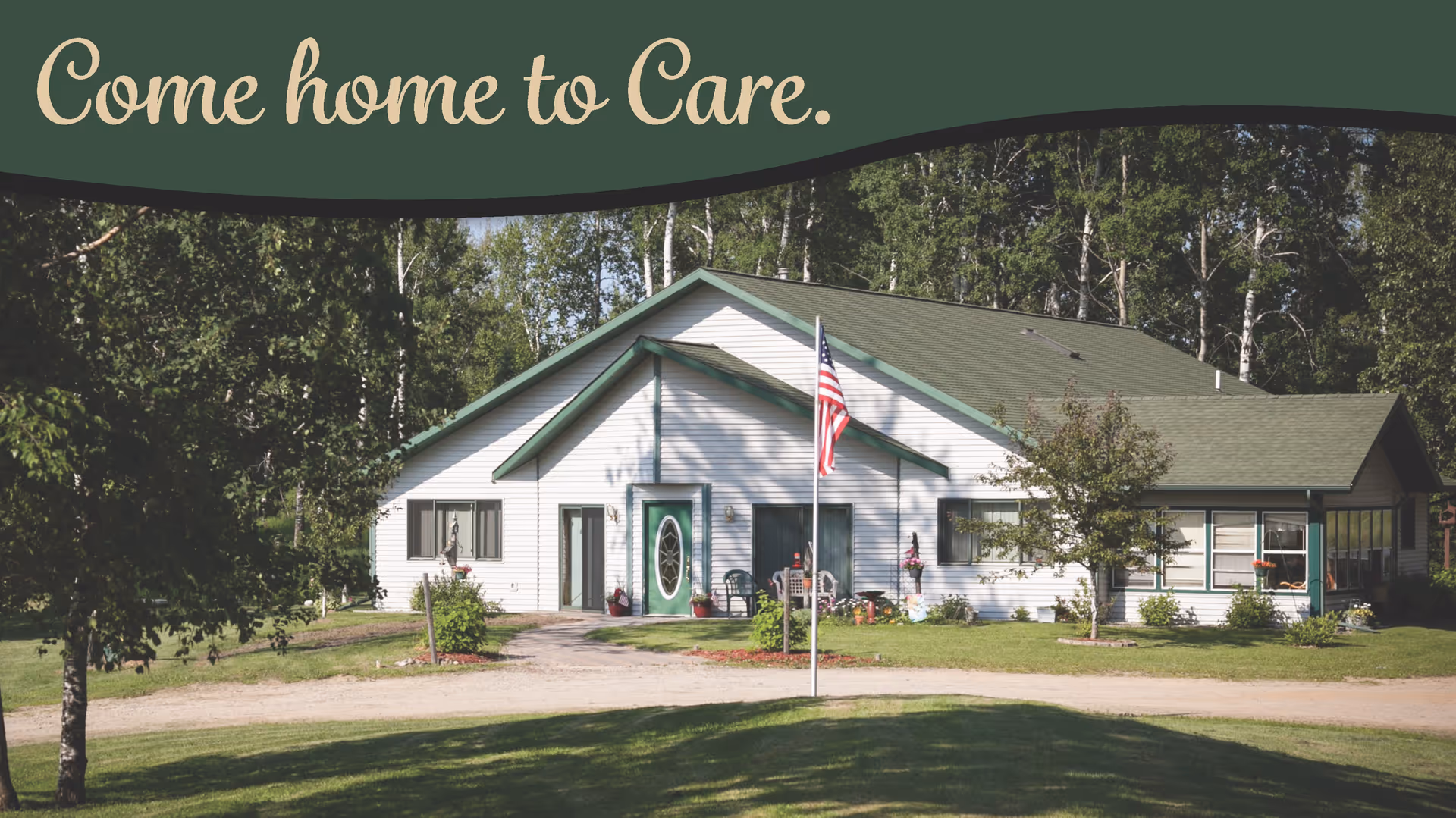 A white single-story building with a green roof surrounded by trees and grass. There is an American flag on a pole in front of the building. Text at the top reads 'Come home to Care.'