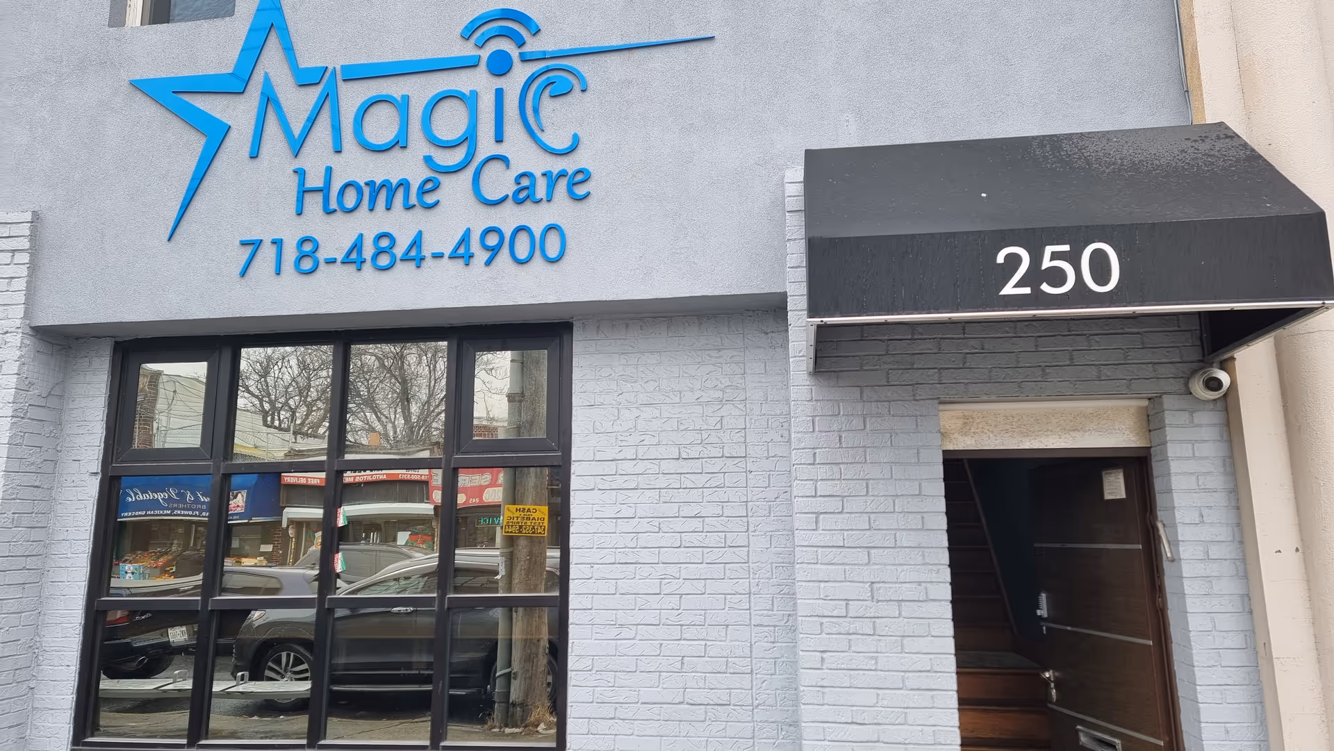 Exterior view of Magic Home Care building with blue sign and entrance.