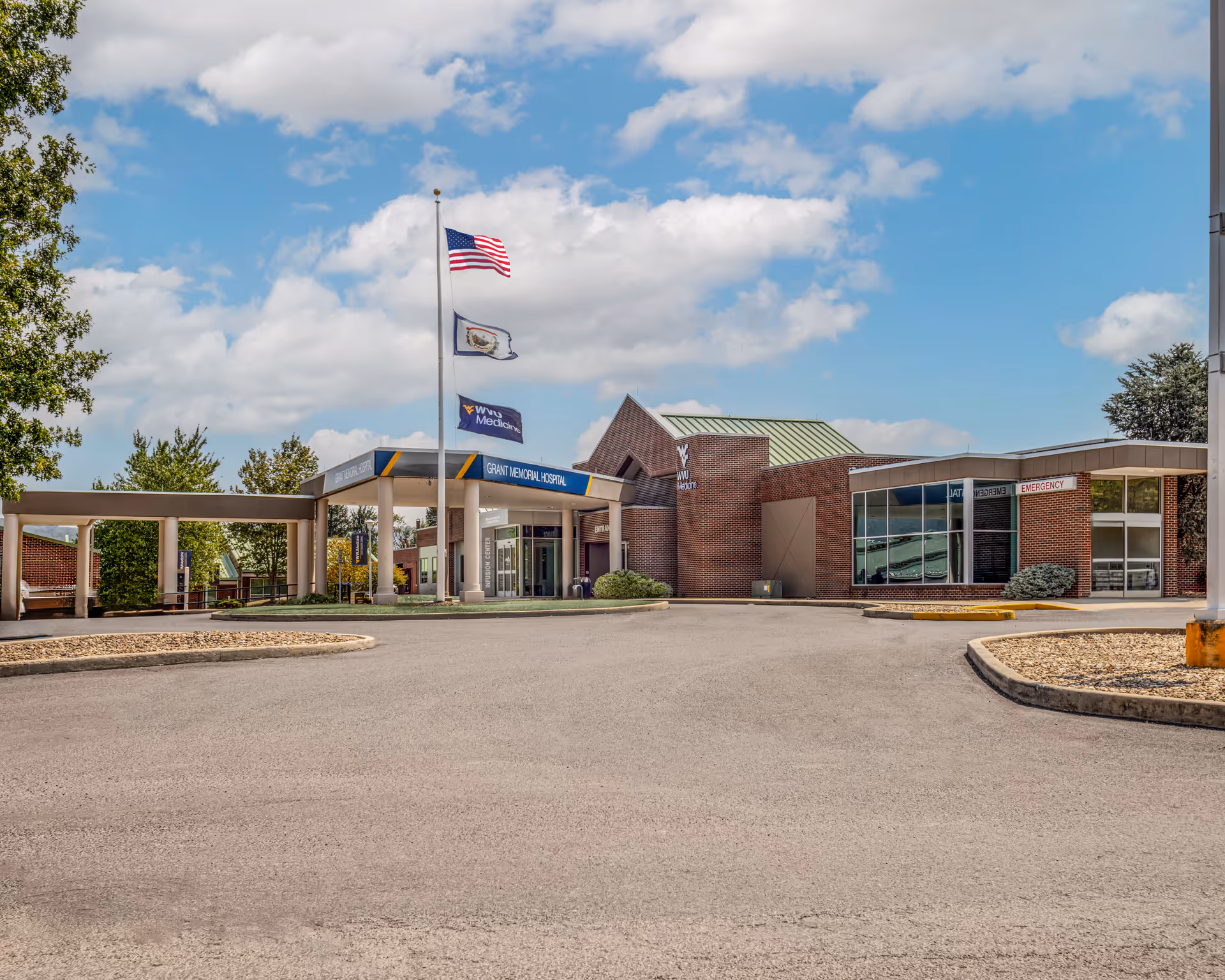 Front view of WVU Medicine Grant Memorial Hospital entrance with flags and driveway