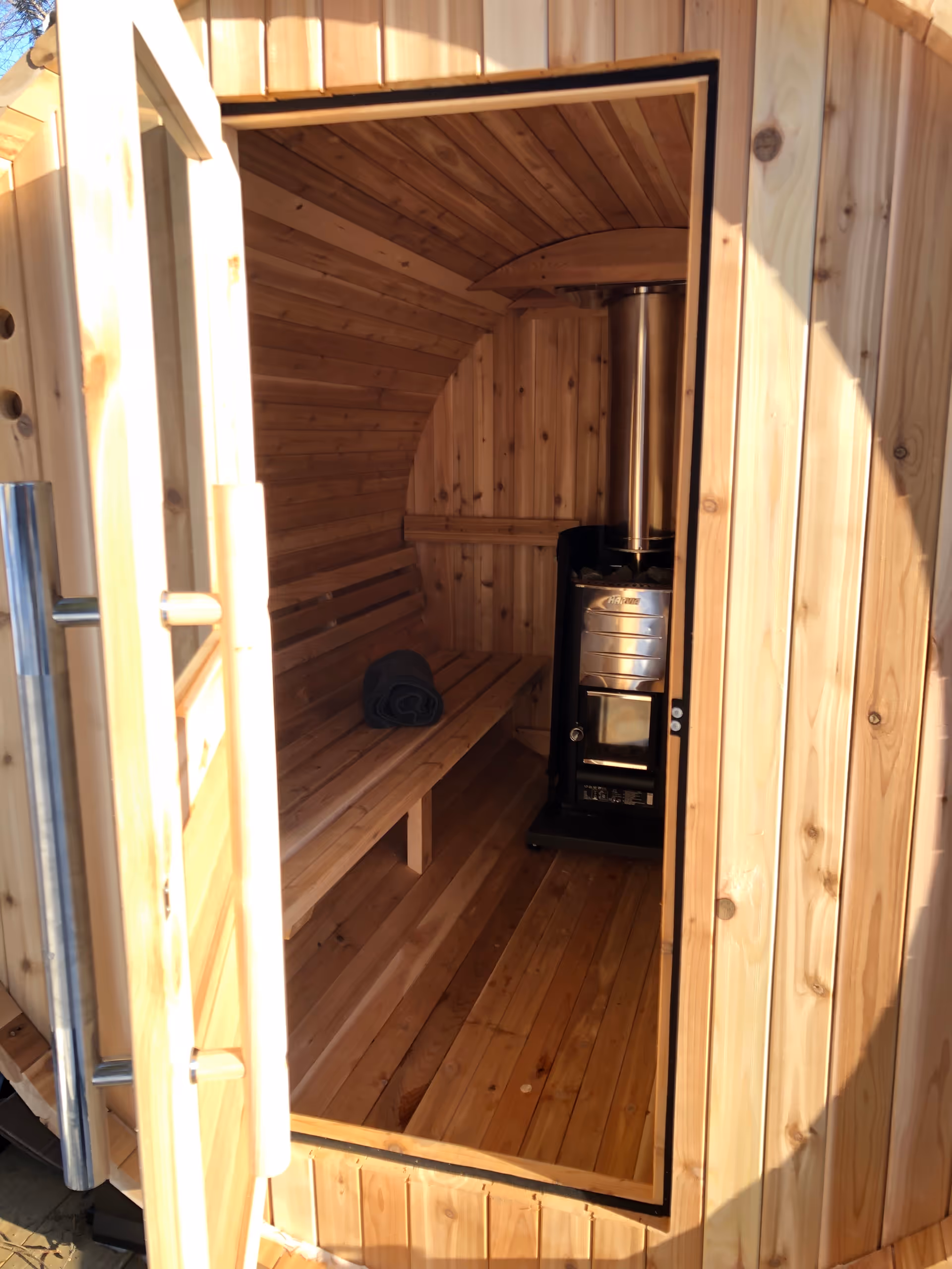 A wooden sauna interior with benches and a metal stove.
