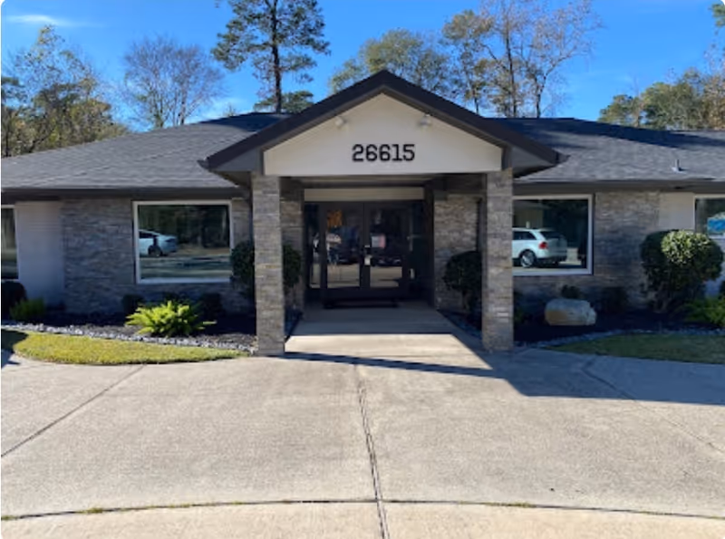Front view of a single-story senior facility with glass doors and address 26615.