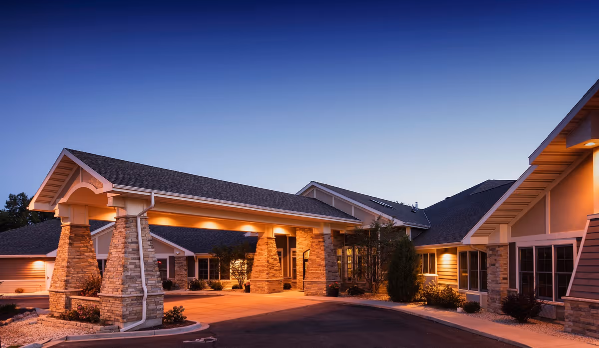 Exterior view of Mission Creek Senior Living entrance with stone pillars and evening lighting.