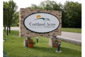 Brick Cortland Acres Nursing Home sign on a grassy roadside area.