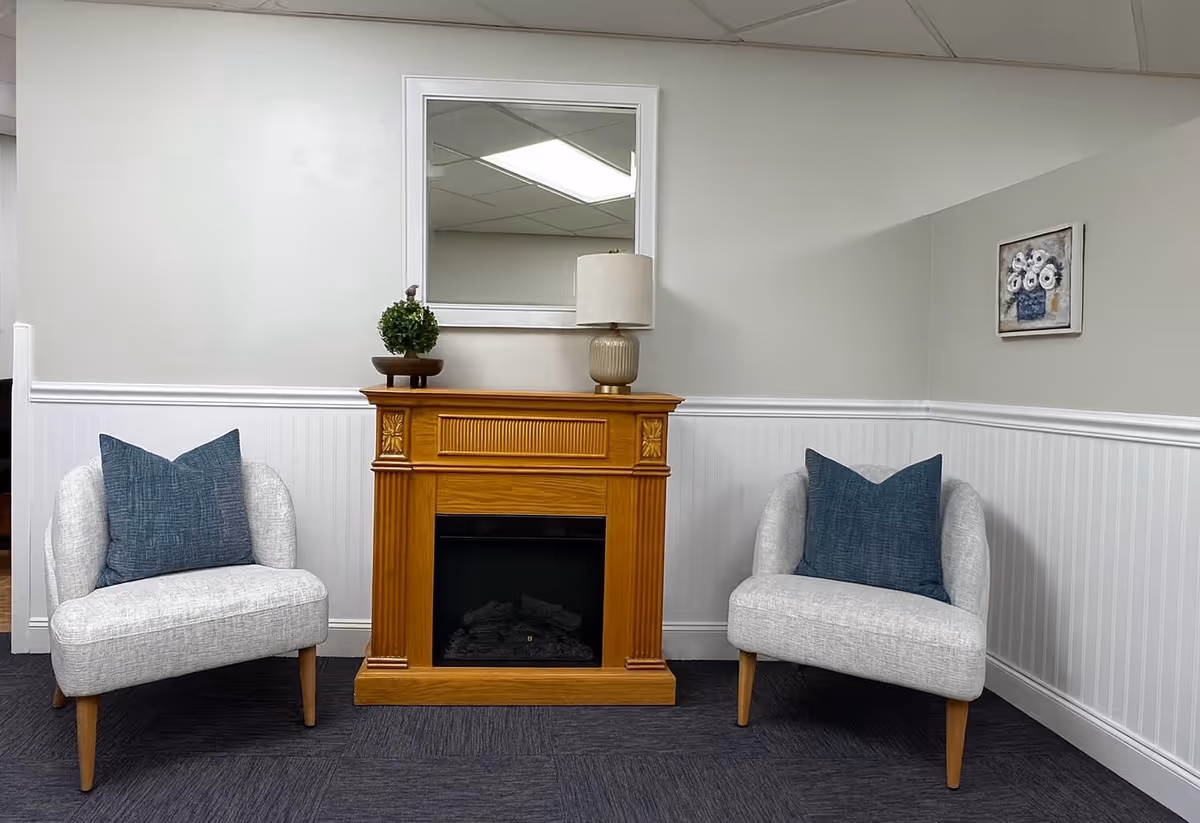 Small, well-lit living room with two cushioned chairs flanking a wooden fireplace.