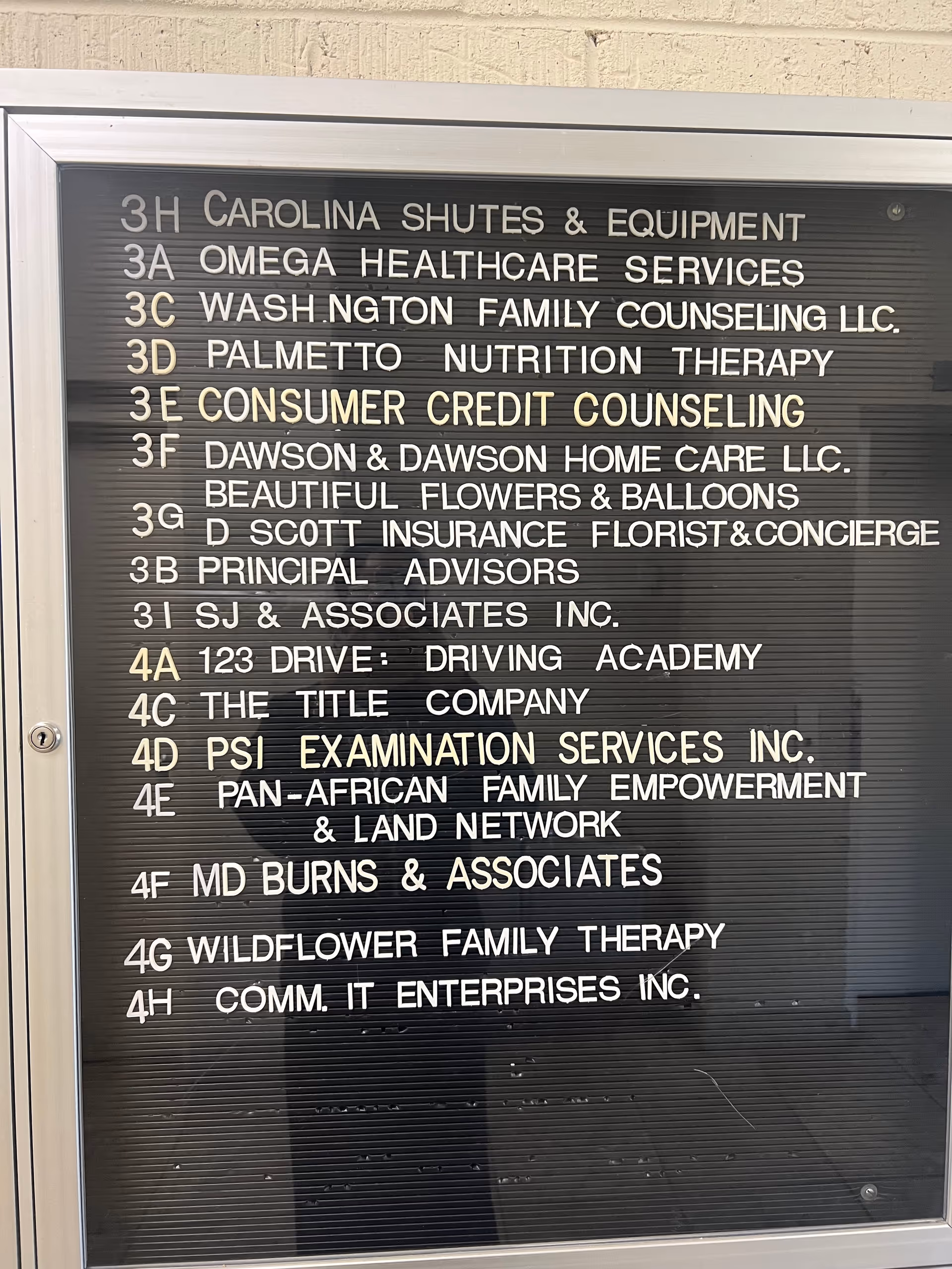 Metal-framed directory board listing office names inside a multi-tenant building.