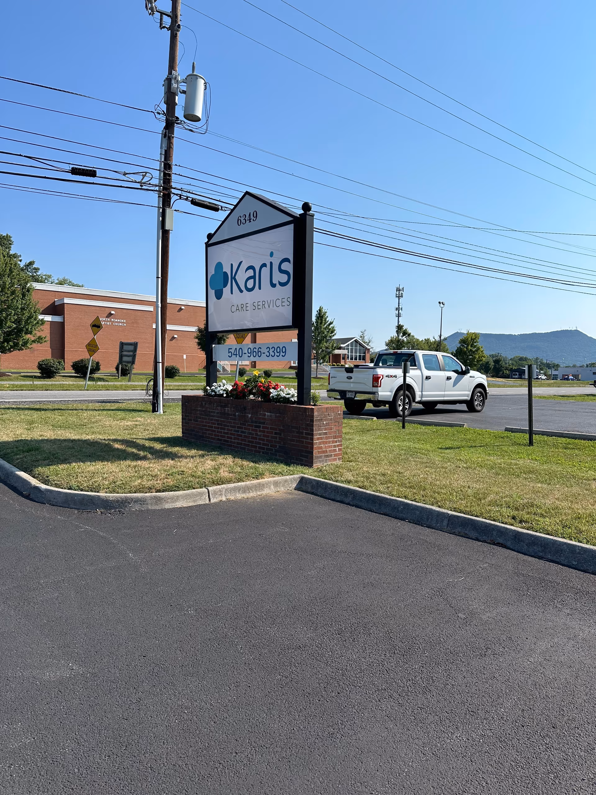 Karis Care Services sign in front of building beside a brick planter and truck.