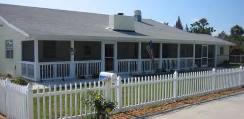 GrandCare Assisted Living front view: single-story home with white picket fence and porch.