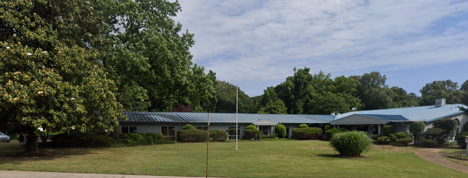 Exterior view of AHC Bright Glade, a single-story senior living facility with a blue roof.