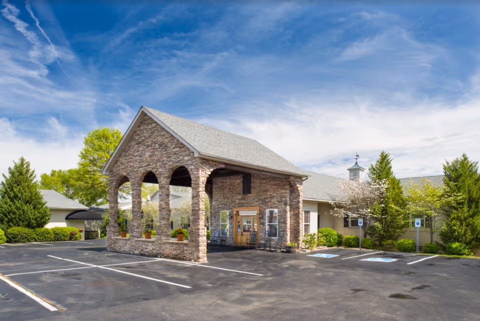 Stone arched entrance of River Oaks Place Lenoir City with a parking lot.